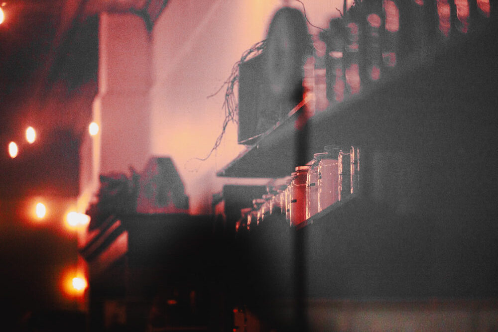 An abstract, moody photo looking through the window of Little Willow Mercantile at night, with a warm red glow from inside.